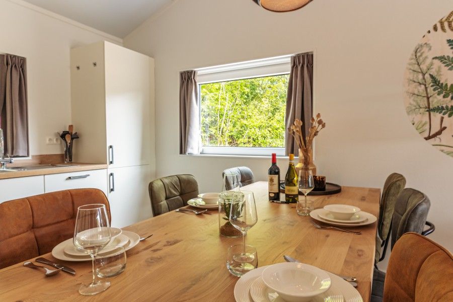 Dining table in Nesserduinen 42D, vacation home in Nes, Ameland overlooking green surroundings.