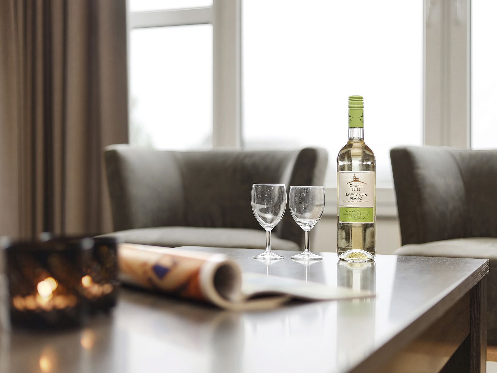 Stijlvolle zithoek in Ameland State appartement in Nes, Ameland, met wijn en glazen op de tafel.