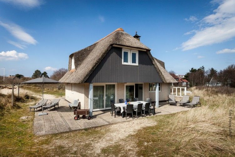 Zonnig terras van Villa Rietberg op Schiermonnikoog, vakantiehuis met buitenzitje en natuur.