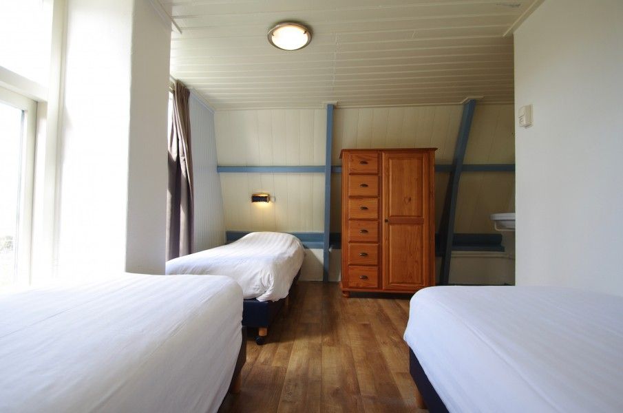 Ruime slaapkamer met drie bedden in Klaver Vier vakantiehuis op Schiermonnikoog.