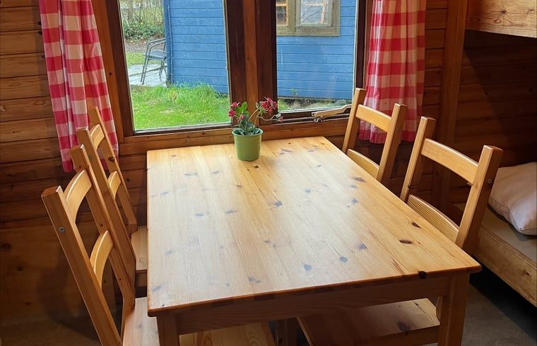 Cozy dining area in Holiday Home in Workum with wooden table and view of green surroundings, ideal for staying near IJsselmeer and Frisian lakes.