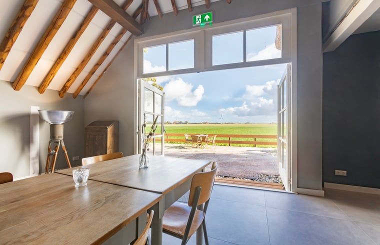 Eetkamer in Vakantiehuisje in Piaam met uitzicht op de tuin en velden, ideaal voor een ontspannen maaltijd aan de Friese meren.