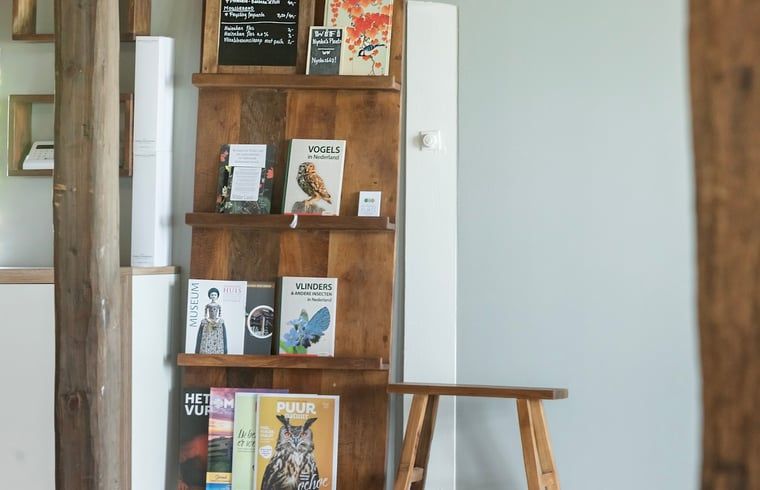 Informatieve boekenhoek in Vakantiehuisje in Piaam met diverse natuurboeken, ideaal voor natuurliefhebbers aan de Friese meren.