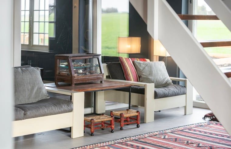 Zithoek bij de trap in Vakantiehuisje in Piaam met uitzicht op groene velden, ideaal voor een rustige middag aan het IJsselmeer.