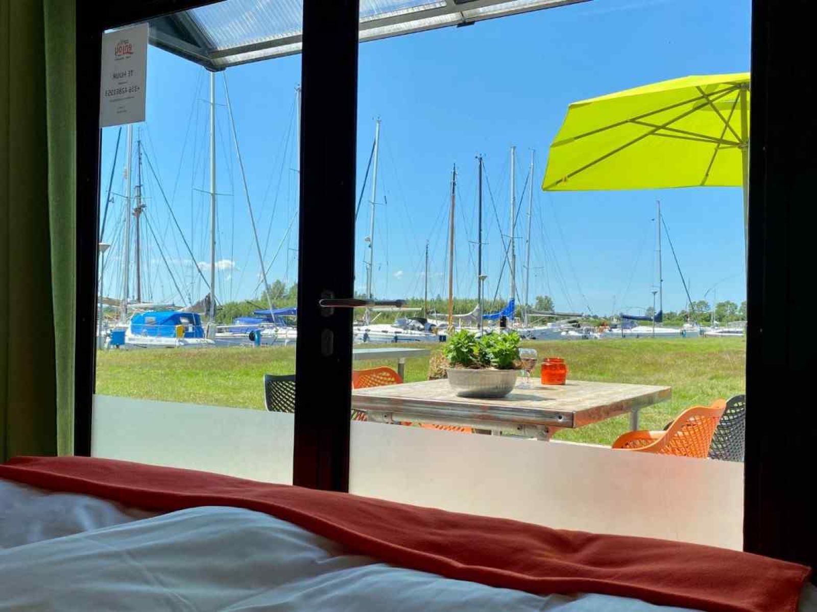 Terrasse des Ferienhauses FR058 in Warns, mit Blick auf den Yachthafen und die gruene Umgebung.