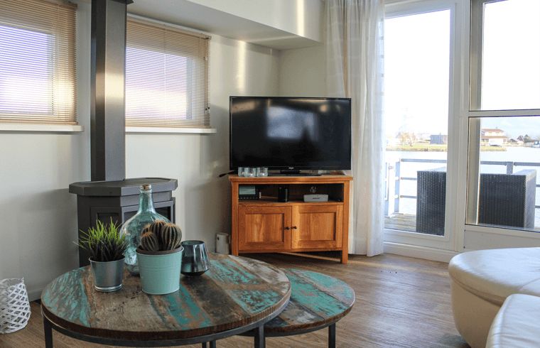 Cozy living room in Holiday Home in Oudega overlooking Heeg Lake, Frisian Lakes, equipped with wood stove and modern furnishings.