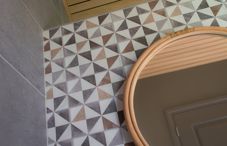 Modernes Badezimmer im Ferienhaus in Koudum mit geometrischen Fliesen und elegantem Spiegel.