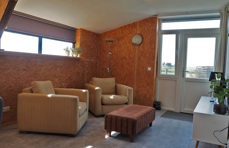 Gezellige eetruimte in Vakantiehuisje in It Heidenskip, gelegen aan de Friese meren, met houten tafel en comfortabele stoelen.