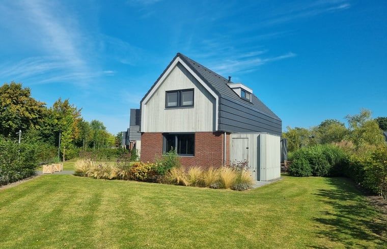 Modernes Ferienhaus in Balk, umgeben von viel Gruen und blauem Himmel, ideal fuer einen erholsamen Aufenthalt am Slotermeer.