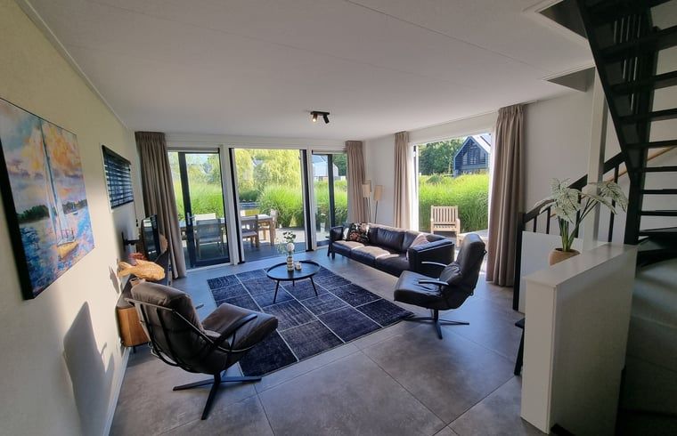 Geraeumige Sitzecke im Ferienhaus in Balk mit bequemen Stuehlen und viel natuerlichem Licht, in der Naehe von Slotermeer.