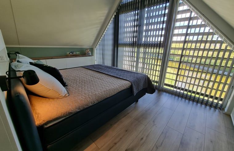 Gemuetliches Schlafzimmer im Ferienhaus in Balk mit grossem Fenster und Blick auf die Natur, in der Naehe des Slotermeers.