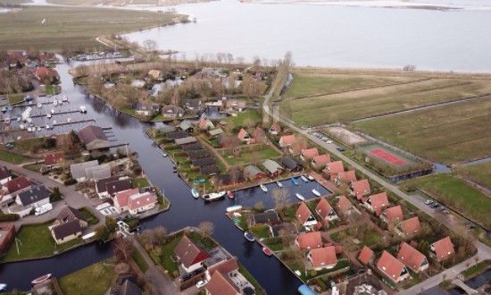 Aerial view of Bungalow Sneekermeer with sailboat in Goingarijp, located on the waters of the Frisian lakes for a relaxing vacation.