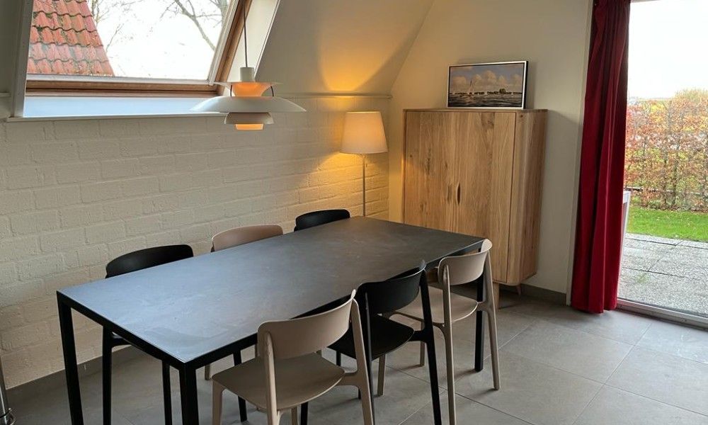 Cozy dining area in Bungalow Sneekermeer, Goingarijp. Vacation home with modern furnishings and garden views near Frisian lakes.