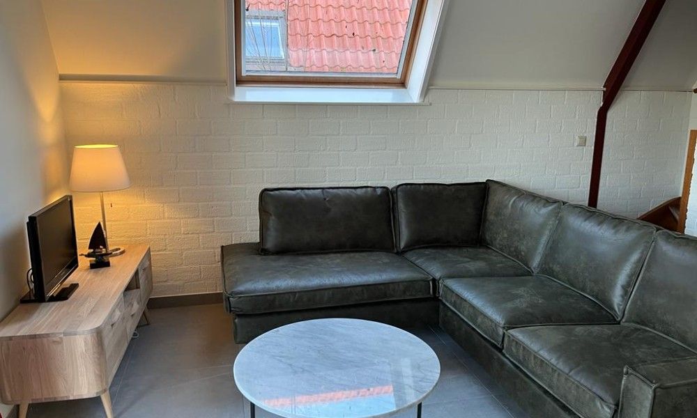 Cozy living room in Bungalow Sneekermeer, Goingarijp. Comfortable sitting area with natural light and modern decor near Frisian lakes.