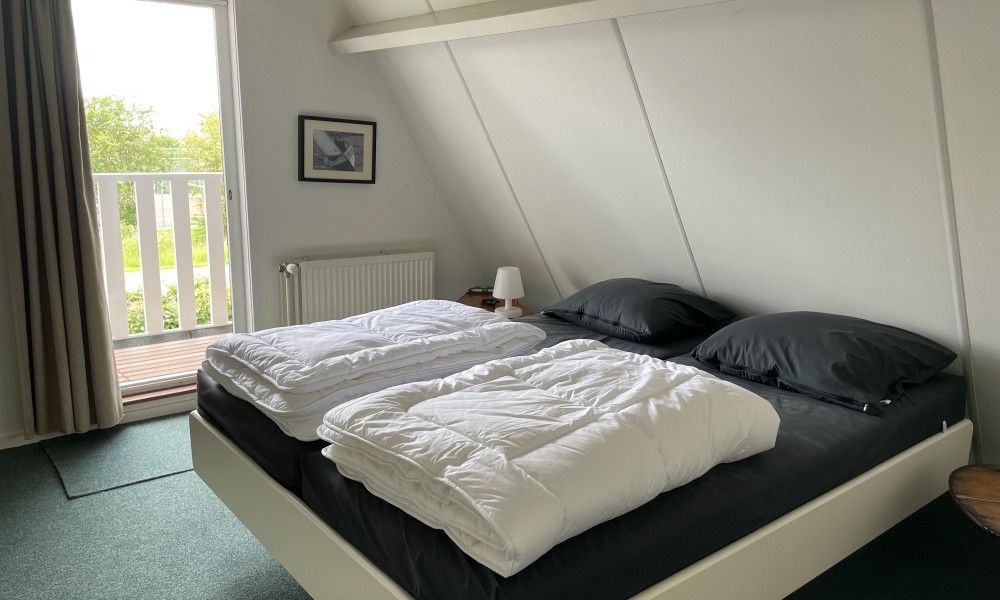 Attractive bedroom in Bungalow Sneekermeer, Goingarijp overlooking balcony and green surroundings by the Frisian lakes.