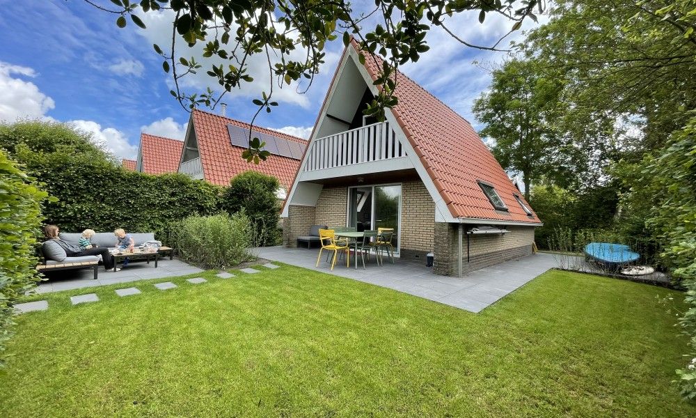 Enjoy the terrace of Bungalow Sneekermeer in Goingarijp, located near the Frisian lakes, with a beautiful view of the green garden.