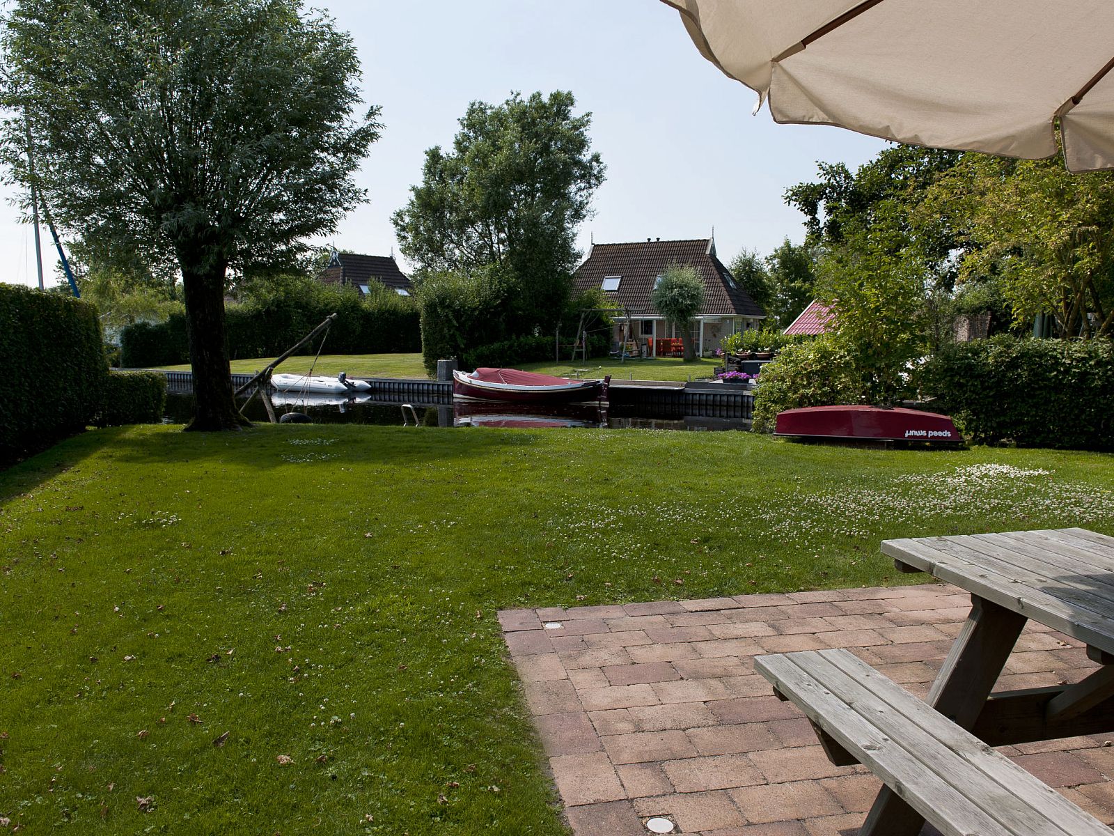 Groene tuin met uitzicht op het water bij Vakantiehuis Bungalowpark It Wiid, ideaal voor ontspanning in Earnewald.
