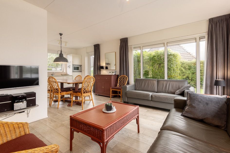 Spacious living room of Wetterbungalow 6 in Earnewald, Frisian Lakes, with comfortable seating area and views of the green surroundings.