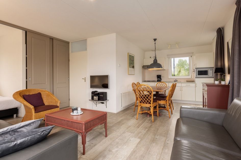 Cozy living room of Wetterbungalow 6 in Earnewald, Frisian Lakes, with comfortable sitting area and spacious kitchen.