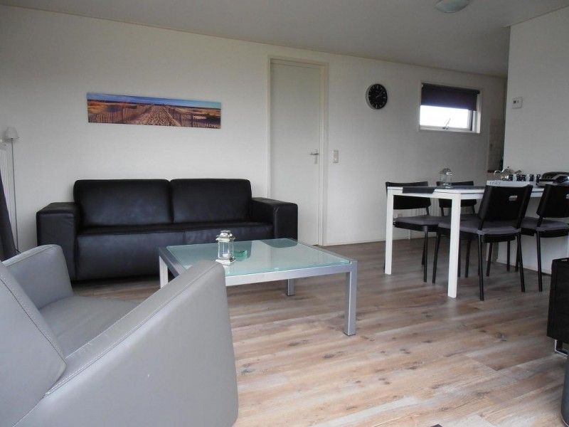 Moderne woonkamer in Vakantiewoningen Oostmahorn, Oostmahorn, met stijlvolle inrichting en veel lichtinval.