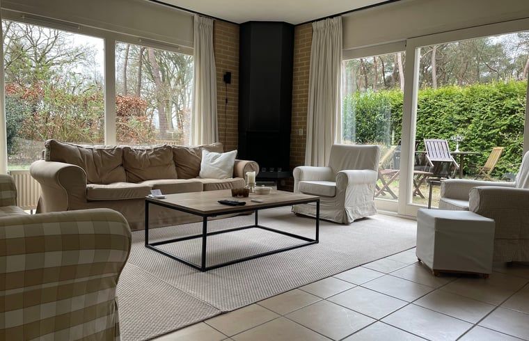 Lichte woonkamer van Vakantiehuis in Spier met uitzicht op de groene omgeving van Drenthe.