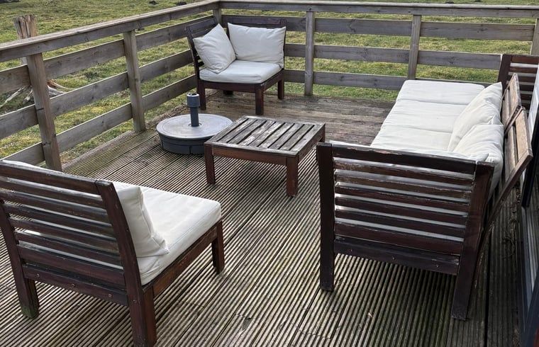 Houten veranda van Vakantiehuisje in Wezuperbrug met uitzicht op groene velden in Midden Drenthe, Drenthe.