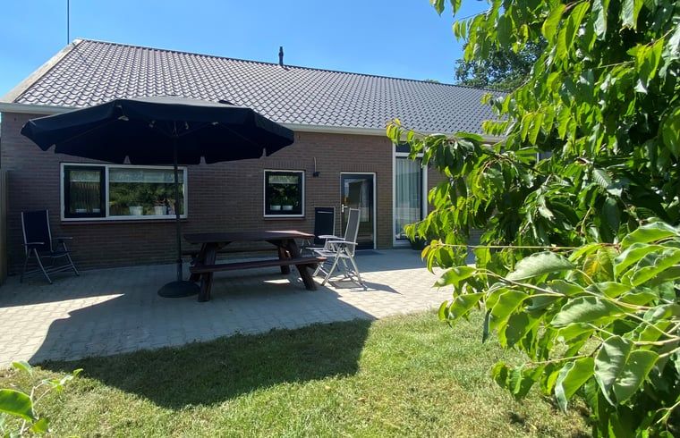 Terrasse mit Sonnenschirm im Ferienhaus in Beilen, Zentral-Drenthe, ideal fuer Mahlzeiten im Freien.