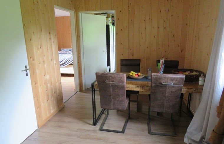 Gezellige eetruimte in Vakantiehuis in Gasselte, Midden Drenthe, met houten interieur en comfortabele stoelen, ideaal voor familiediners.