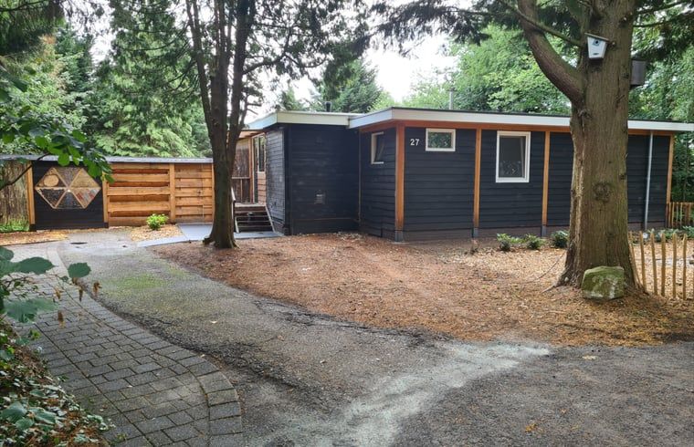 Rustic exterior of Cottage in Gasselte, Drenthe, surrounded by trees and a charming wooden fence.