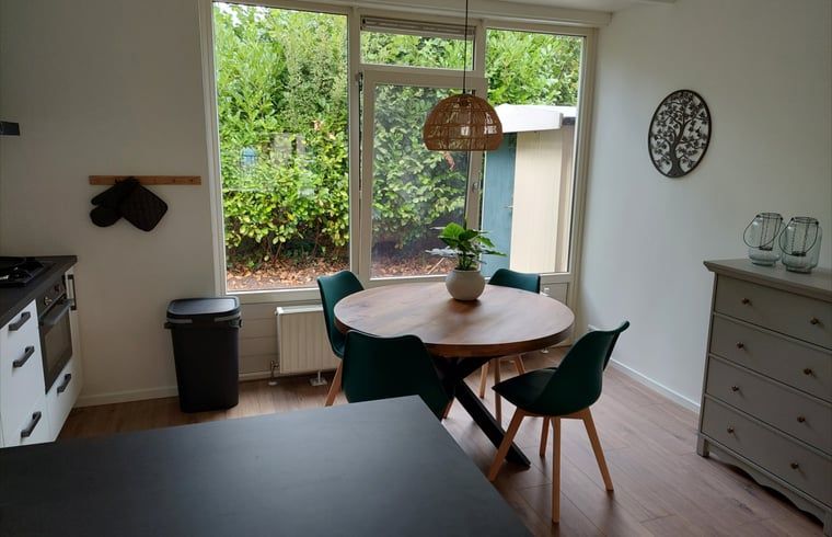 Bright dining room in Holiday Home in Gasselte, Central Drenthe, overlooking green garden, ideal for relaxed meals.