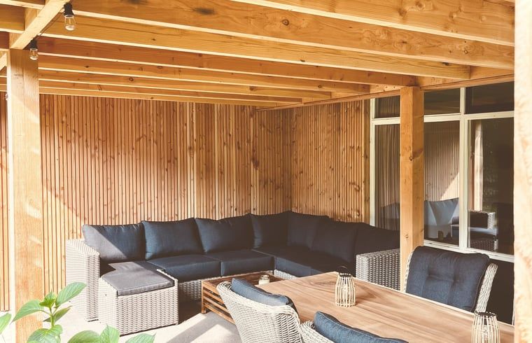 Gezellige veranda van Huisje in Gasselte, vakantiehuis in Midden Drenthe, met comfortabele zithoek en houten afwerking voor ontspanning.