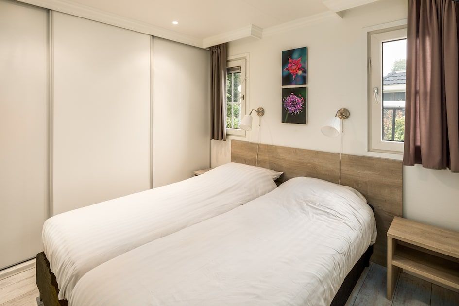 Gezellige slaapkamer in Dotterbloem Chalet 4, een vakantiehuis in Hooghalen, Midden Drenthe, met comfortabele bedden en natuurlijk licht.