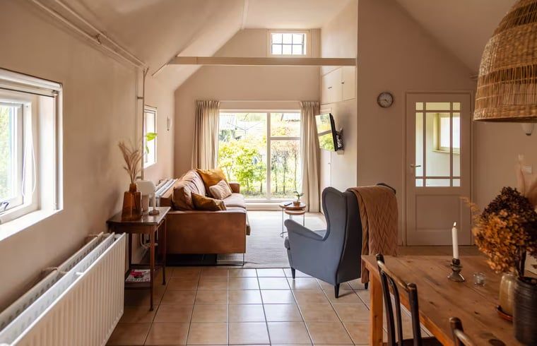 Lichte woonkamer met uitzicht op tuin in Vakantiehuisje in Hooghalen, ontspannen verblijf in Midden Drenthe, Drenthe.