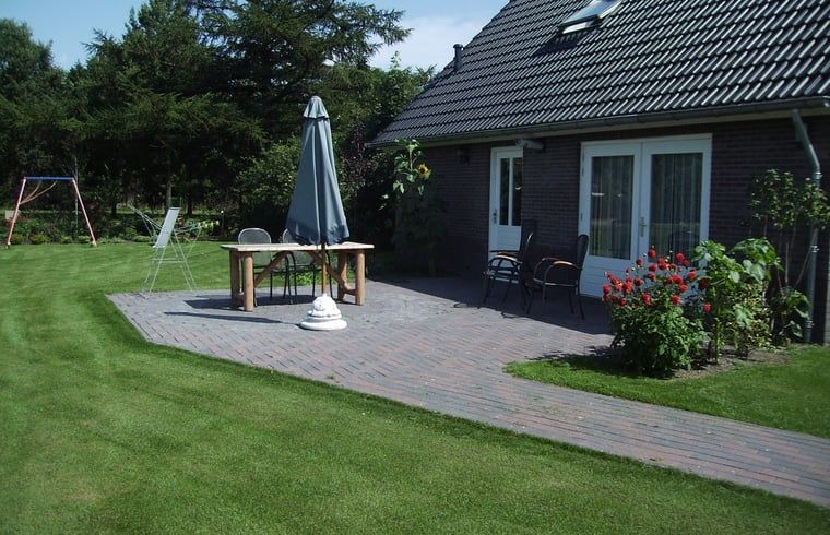 Terras met parasol en tuinmeubilair bij Huisje in Eesergroen, vakantiehuis in Midden Drenthe.