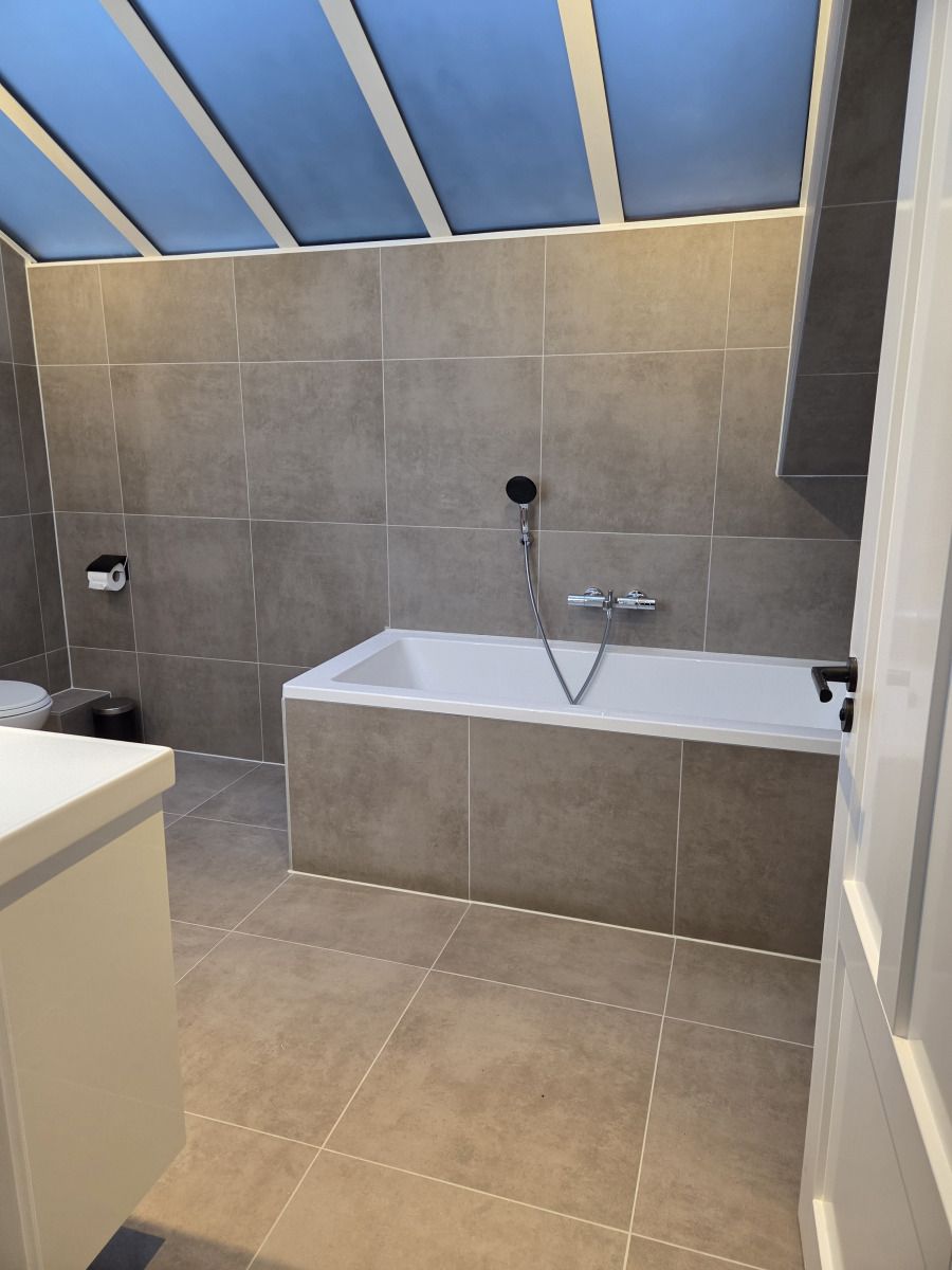 Geraeumiges Badezimmer mit Badewanne im Ferienhaus DG2033, Odoorn, Mid Drenthe, ausgestattet mit luxurioesen Sanitaerobjekten.