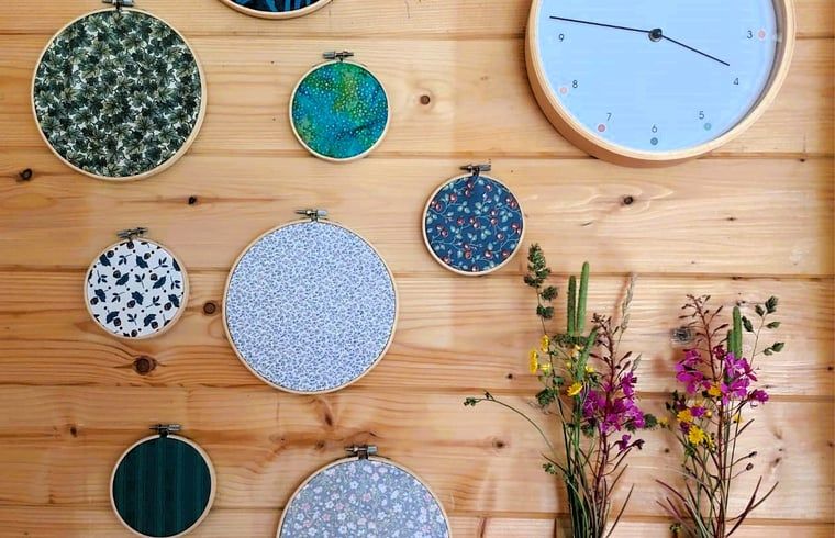 Einzigartige Wanddekoration im Ferienhaus in Nieuw Balinge, Midden Drenthe, mit bunten Stickereiringen und Uhr.