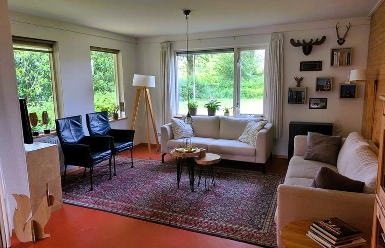 Helles Wohnzimmer im Ferienhaus in Nieuw Balinge, Zentral-Drenthe, mit grossen Fenstern und Blick auf den Garten.