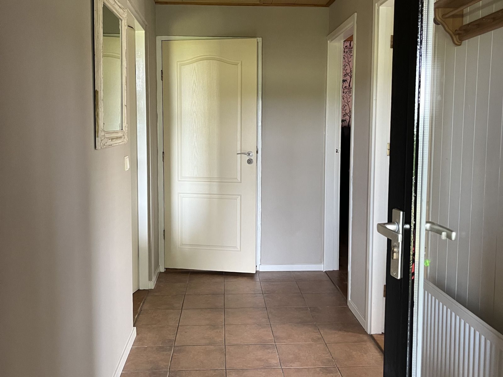 Lichte entree van vakantiehuis DG1879 in Borger, Noord Drenthe met tegelvloer en spiegel.