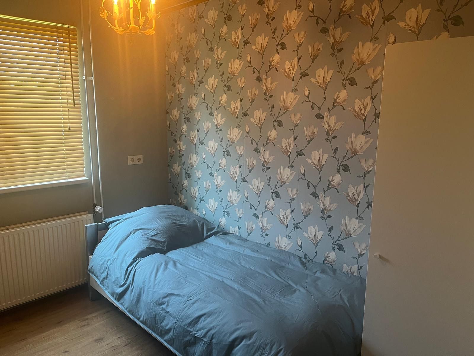 Tweede slaapkamer in DG1879, Borger, Noord Drenthe met blauwe dekens en bloemmotief behang.