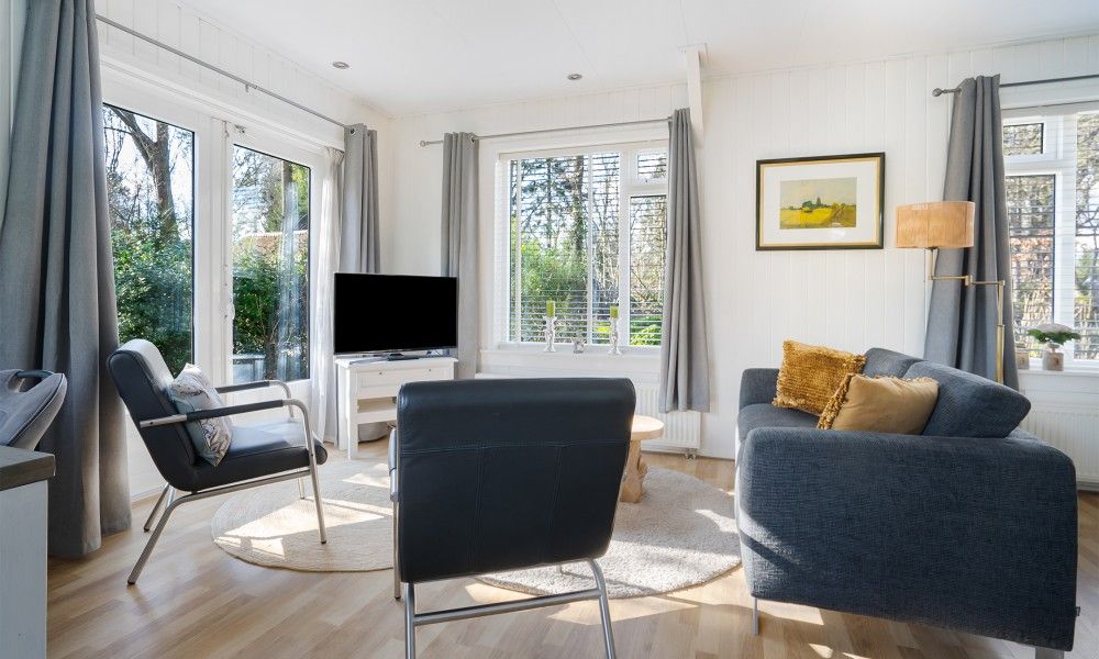 Gemuetliches Wohnzimmer des Ferienhauses Vogelzang in Borger, Drenthe, mit Blick auf den Garten und bequemen Sitzgelegenheiten.