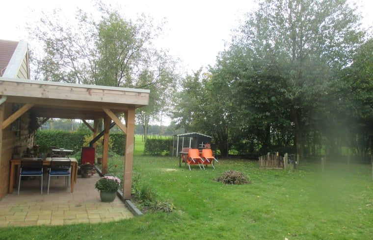 Geniet van de groene tuin en het overdekte terras bij Vakantiehuis in Drouwen, gelegen in het serene Noord Drenthe, Drenthe.