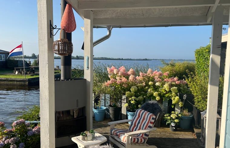 Geniessen Sie die ruhige Veranda des Huisje in Matsloot, einem Ferienhaus am Wasser in Nord-Drenthe, mit schoenem Seeblick.
