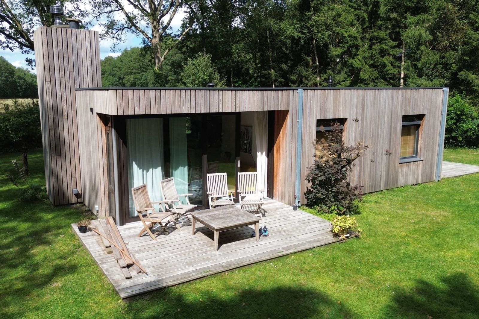 Natuerliche Umgebung des Ferienhauses DG357 in Meppen, Drenthe mit einem Grashuepfer auf einem Stuhl.