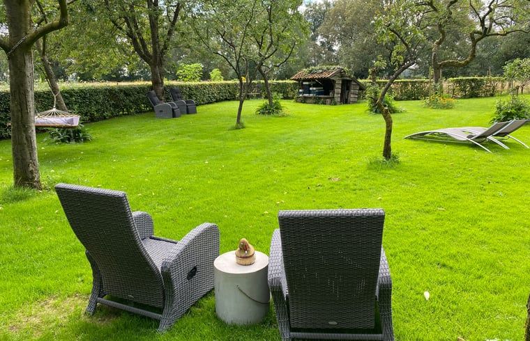 Vakantiehuis in Aalden, groene tuin met comfortabele stoelen in Zuidoost Drenthe, Drenthe.