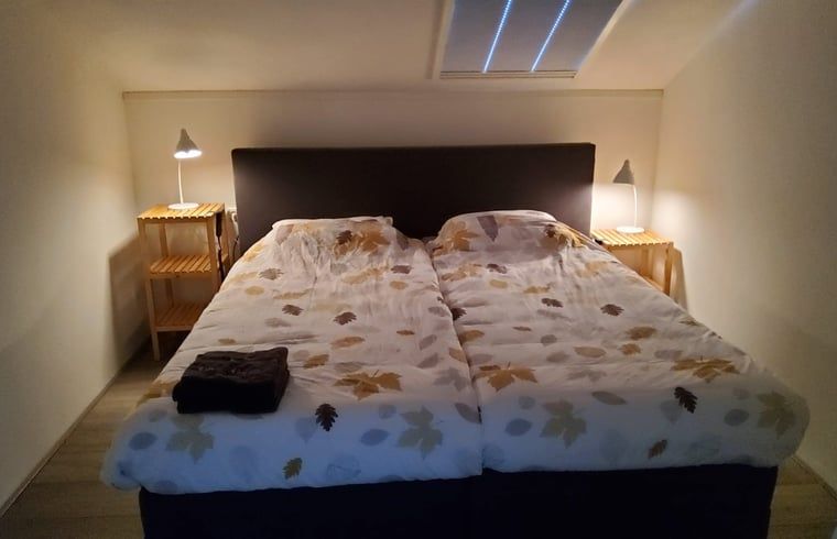 Gemuetliches Schlafzimmer in Cottage in Exloo, Ferienunterkunft in Sued-Ost-Drenthe mit Doppelbett.