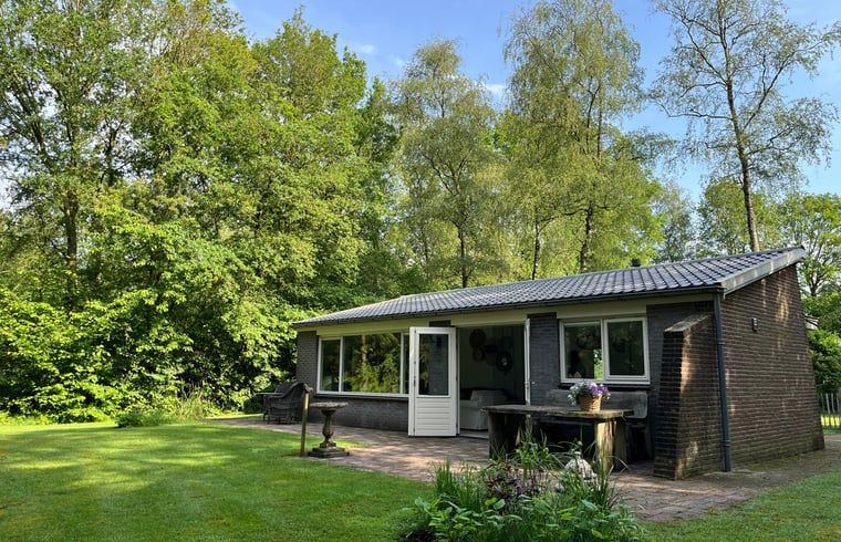 Aussenansicht von Cottage in Gees, Ferienhaus im Suedosten von Drenthe, umgeben von Baeumen und einem Holzzaun.