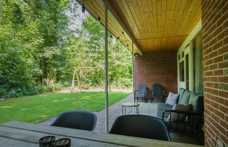 Veranda van Vakantiehuis in Schoonoord, Drenthe met zitgelegenheid en uitzicht op tuin.