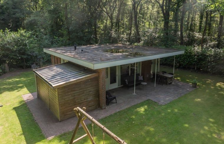 Exterieur van Vakantiehuis in Schoonoord, Zuidoost Drenthe met terras en speeltoestel in bosrijke omgeving.