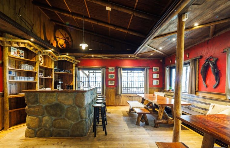 Cozy indoor area of Huisje in Erm, vacation home in Erm, Southeast Drenthe, with rustic wooden furnishings and inviting bar.