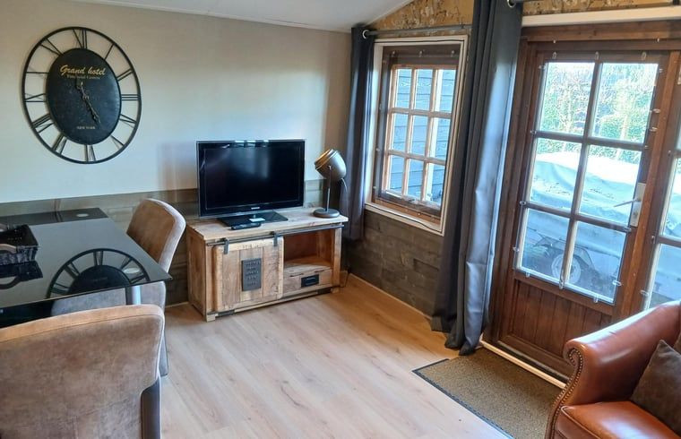 Gezellige woonkamer in Vakantiehuisje in Stieltjeskanaal, Zuidoost Drenthe, met rustieke meubels en uitzicht op de groene omgeving.
